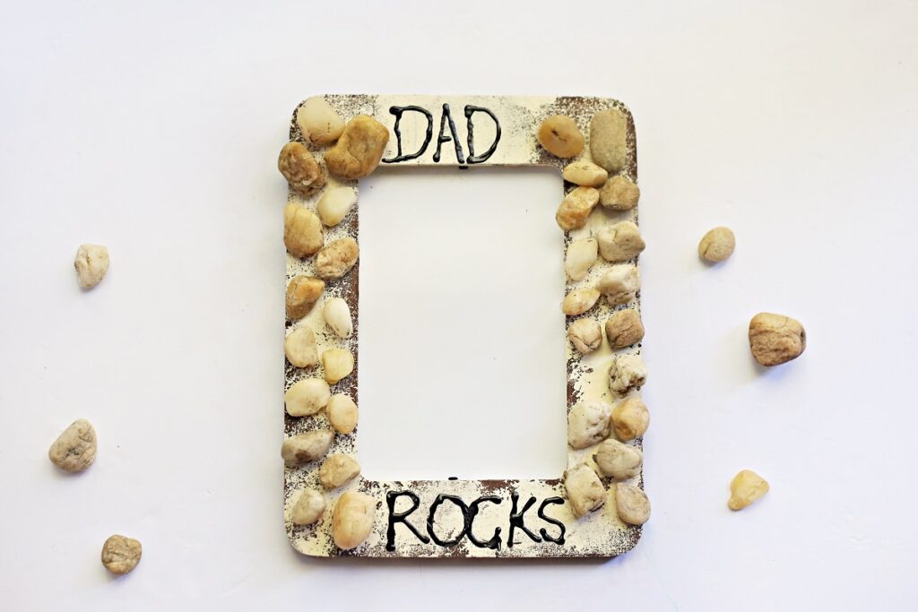 Finished My Dad Rocks craft. The picture frame is painted and glued on rocks resemble rocks cemented in a wall.