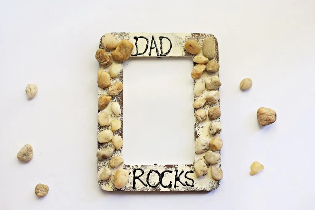 Finished My Dad Rocks craft. The picture frame is painted and glued on rocks resemble rocks cemented in a wall.