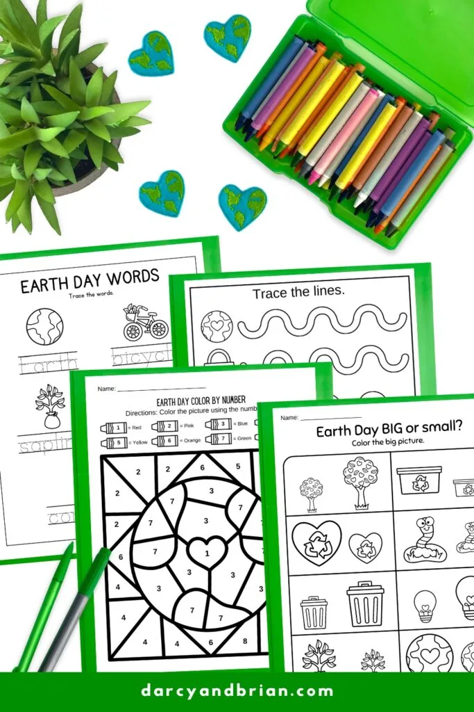 Mock up with four Earth day themed pages on green paper. Crayons and decorative heart shaped Earths nearby.