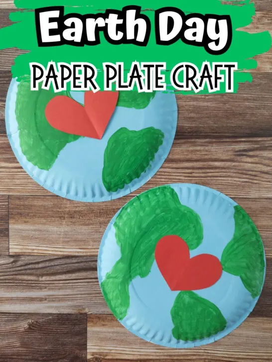 Two large paper plates painted blue and green with red hearts in the middle laying on a wooden table. Top says Earth Day Paper Plate Craft on a green brush stroke background.