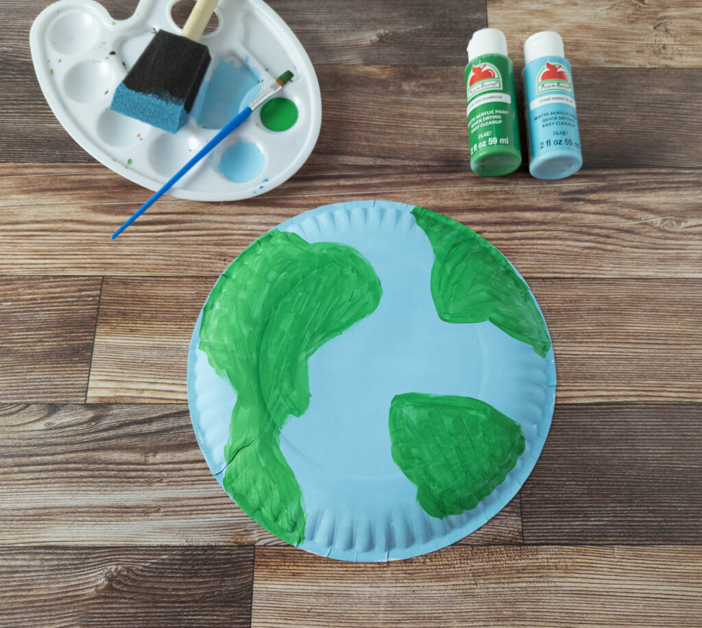 Back of large paper plate painted blue and green like the Earth.