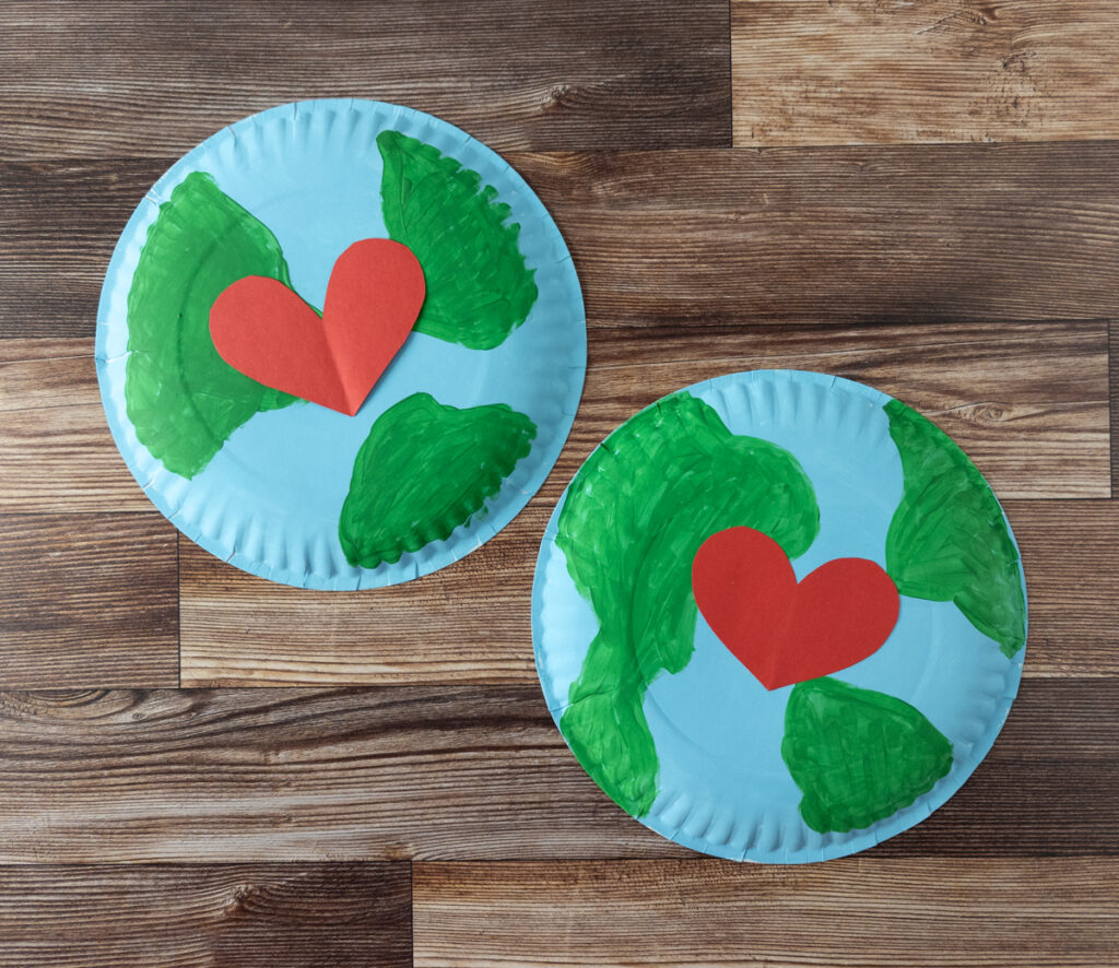 Overhead view of two blue and green painted paper plates with red paper hearts in the center.
