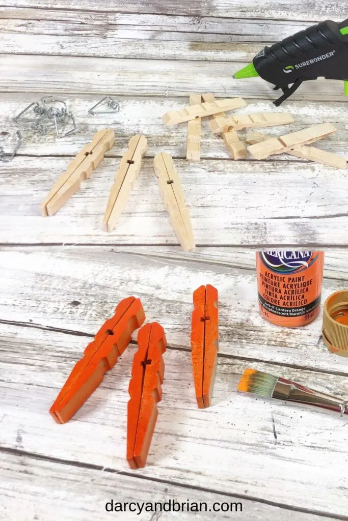 Top image shows wooden laundry clips with springs removed. Bottom photo shows the wooden pins glued together and painted orange.
