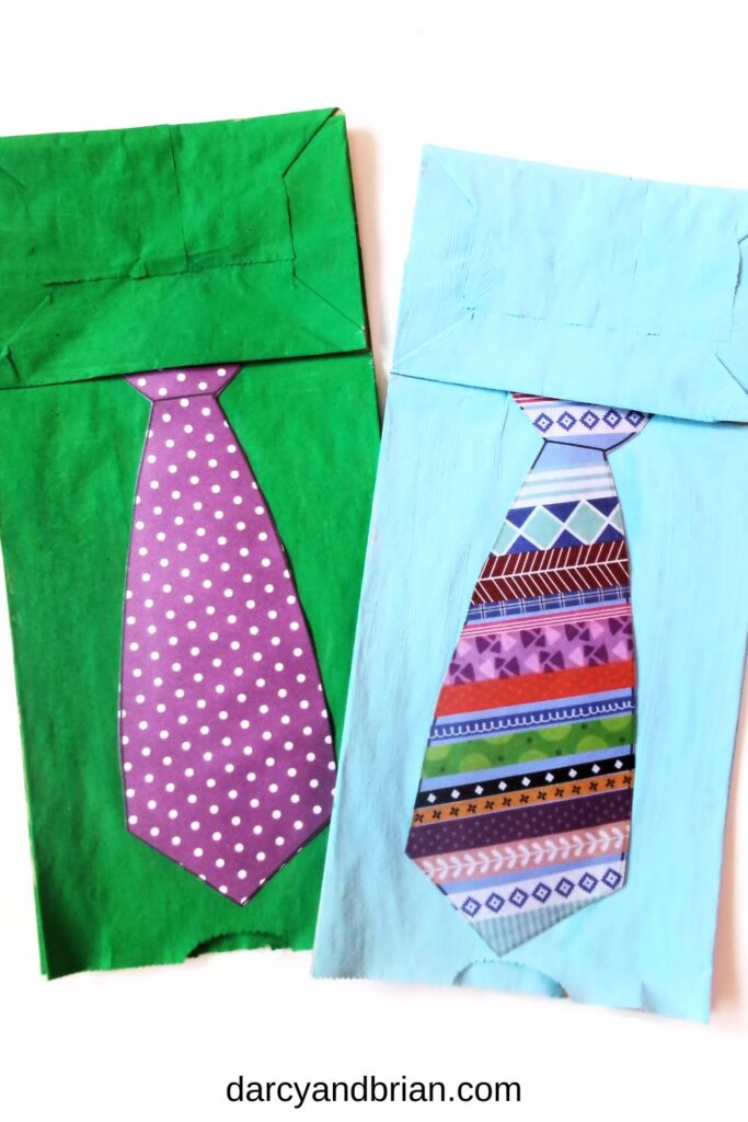 Two finished Father's Day tie crafts made out of paper bag, paint, and cardstock laying next to each other.
