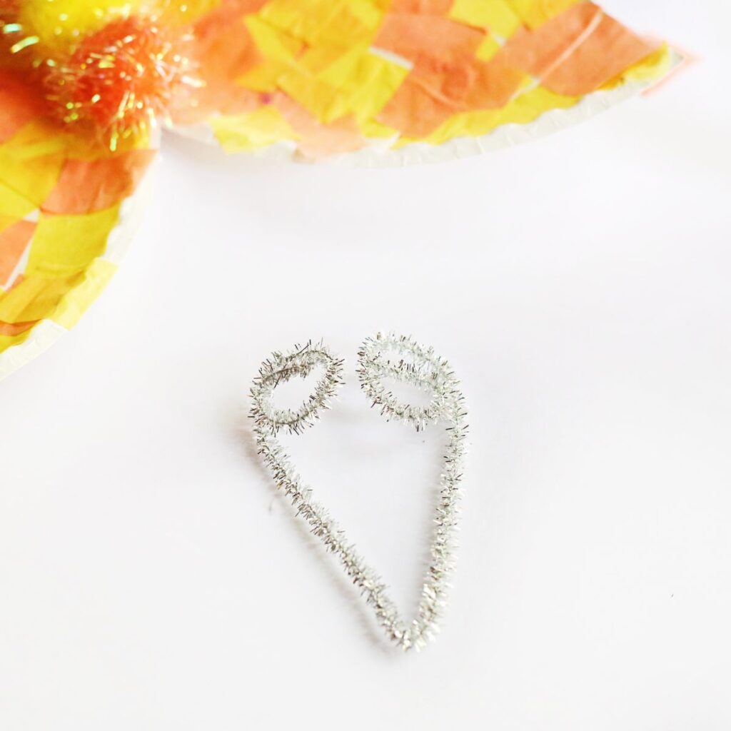 Silver pipe cleaner bent in half like a "v" with ends curled to create antennae.