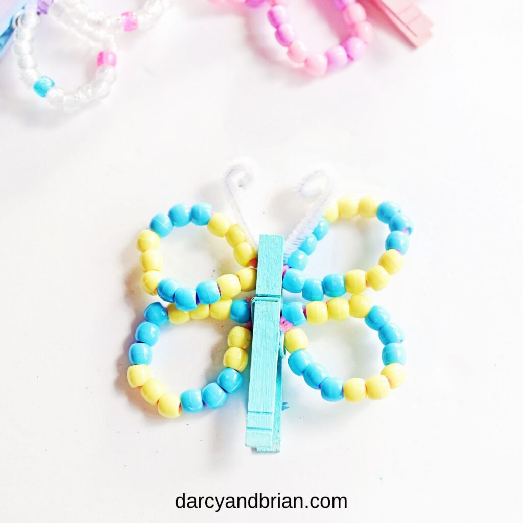 Finished blue and yellow butterfly clothespin craft. Different colors of beaded wings along the top edge.
