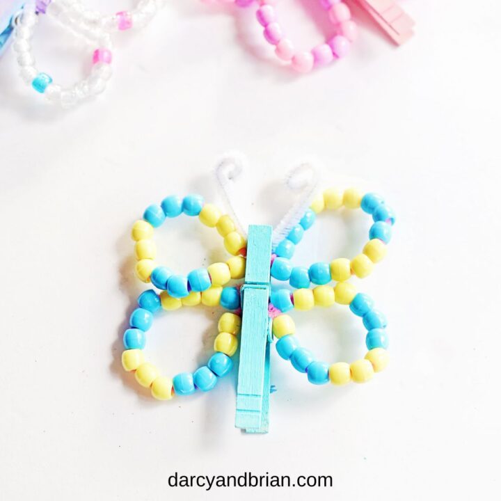 Finished blue and yellow butterfly clothespin craft. Different colors of beaded wings along the top edge.