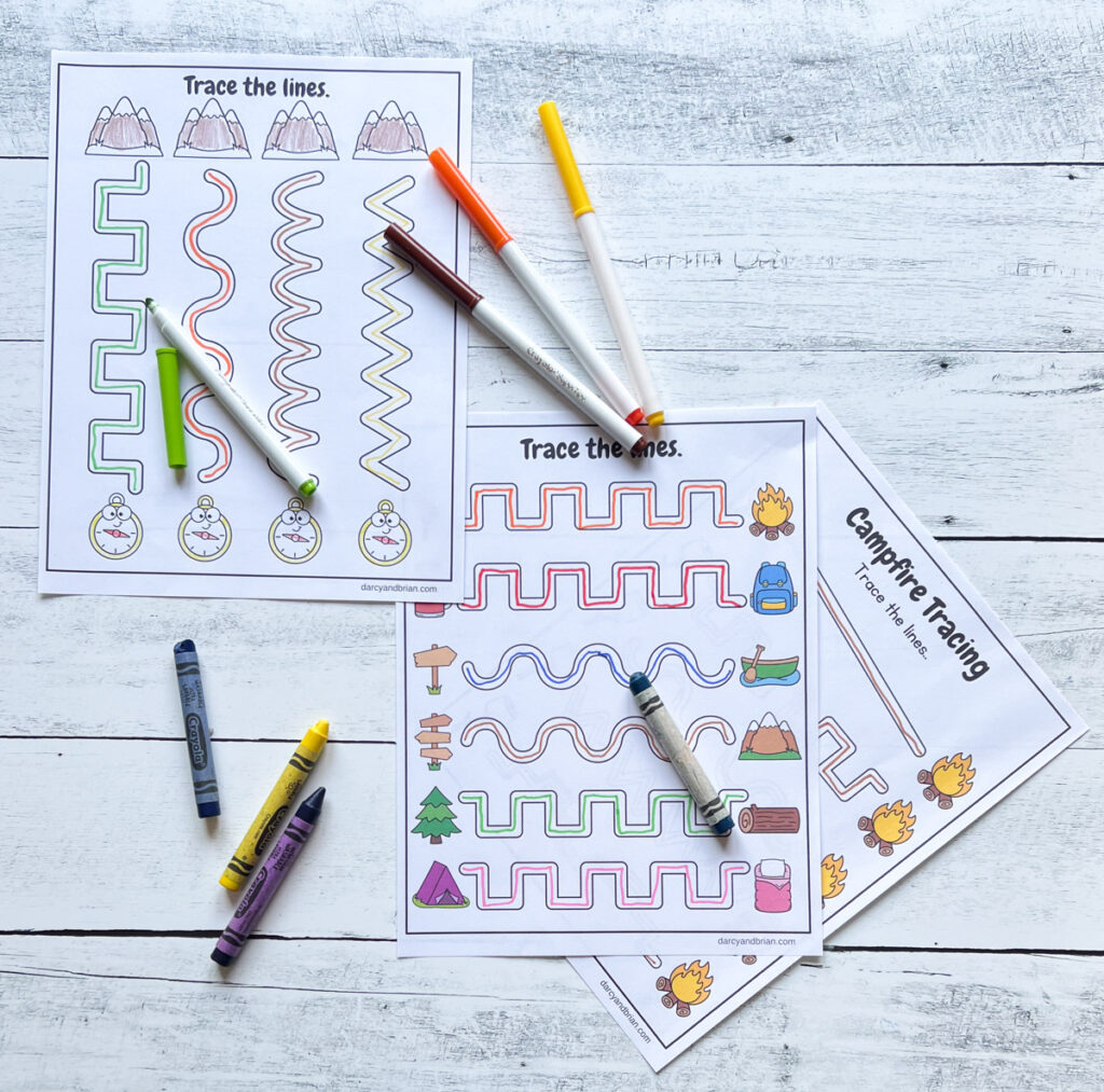 Markers in assorted colors spread out over line path worksheets with camp related pictures.
