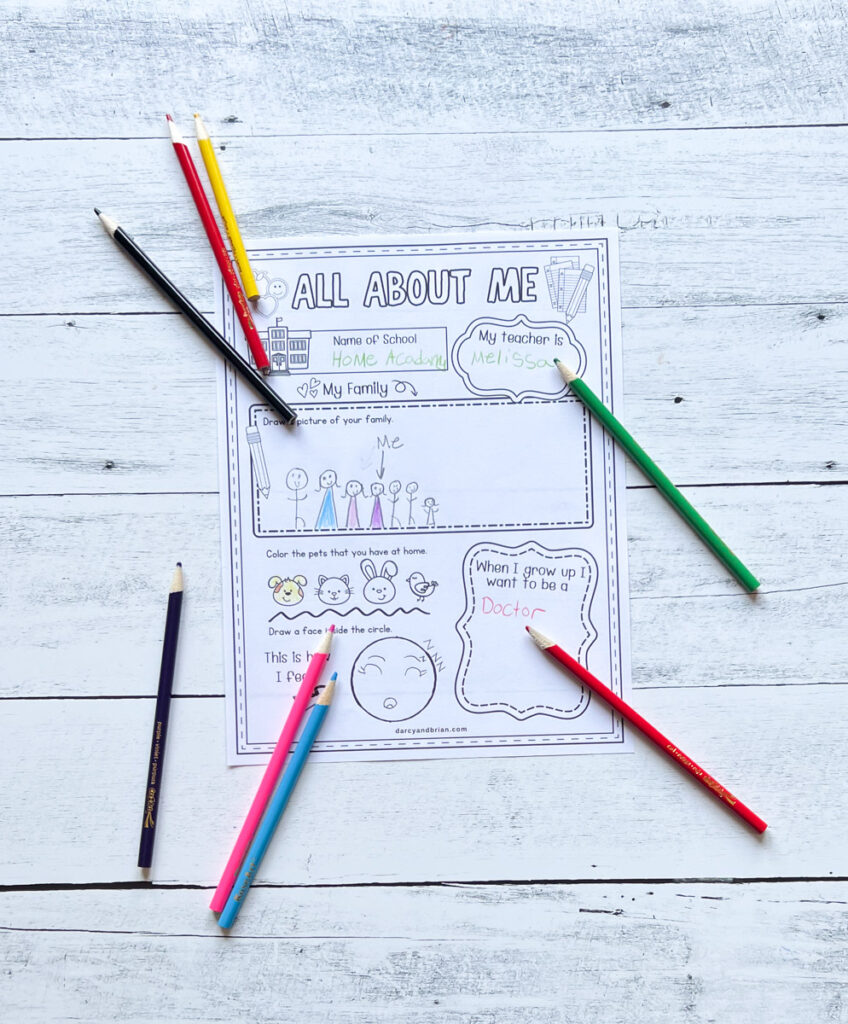 Worksheet with a child's drawing of their family. Assorted colored pencils lay around the paper.